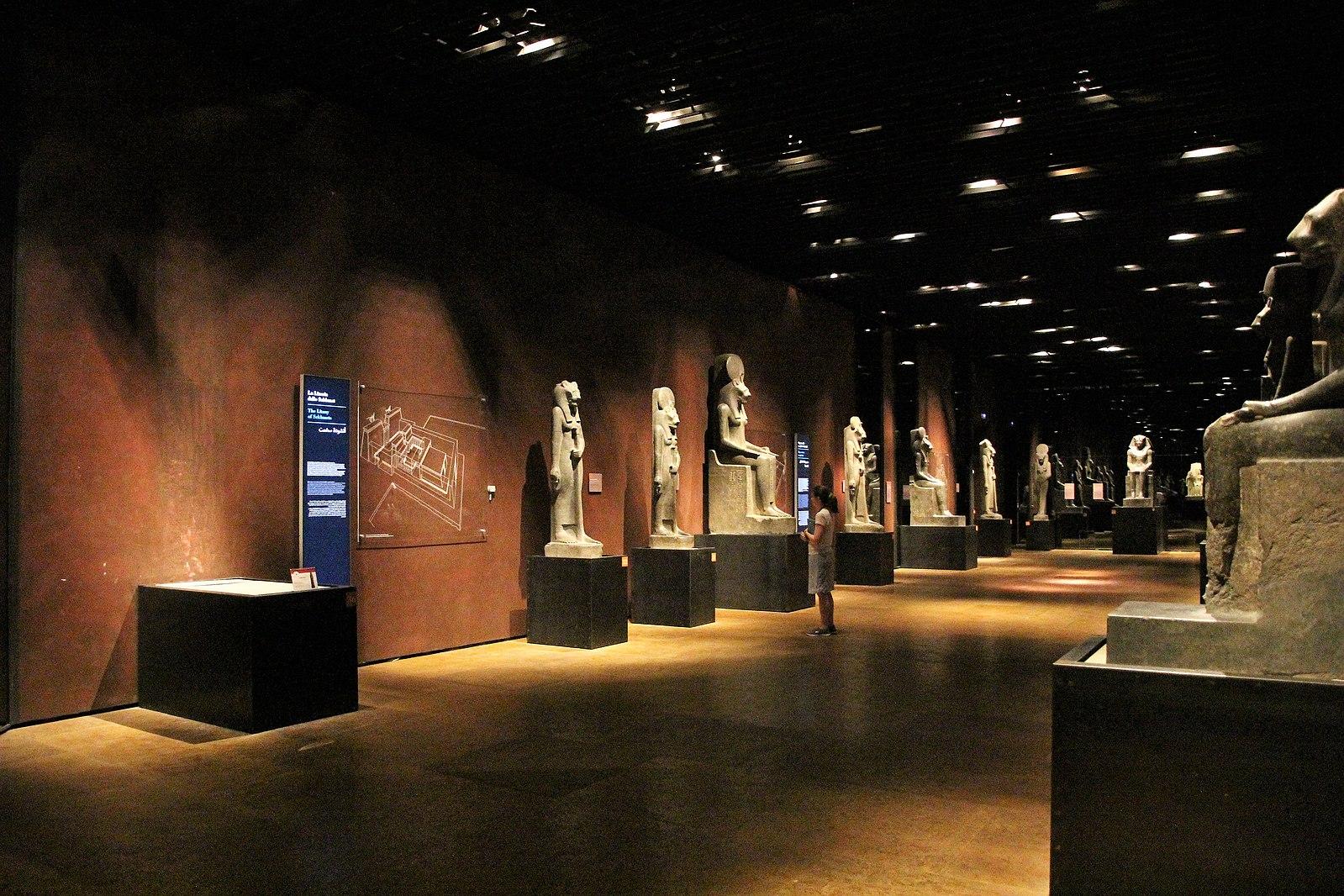 Una sala dello statuario del Museo Egizio. Lungo le pareti sono sistemate alcune statue di grandi dimensioni raffiguranti personaggi dell'antico egizio nelle caratteristiche posture, sia in piedi che sedute.